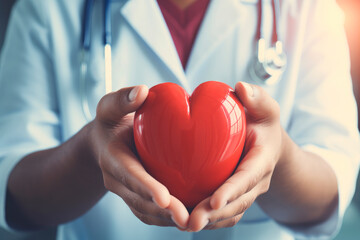 Close up hands of doctor holding red heart shape in a hospital office