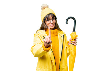 Canvas Print - Young caucasian woman with rainproof coat and umbrella over isolated chroma key background showing and lifting a finger