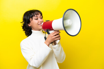 Wall Mural - Young Argentinian woman isolated on yellow background shouting through a megaphone to announce something