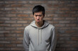 Anger Asian Man In Gray Sweatshirt On Brick Wall Background. Сoncept Managing Anger, Asian Men In Media Representation, Gray Sweatshirts Fashion And Comfort