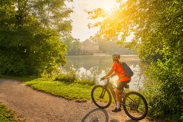 Wall Mural - nice woman with electric mountain bike, cycling in moody morning light on the Neckar valley bicycle path near Ludwigsburg, Baden Württemberg, Germany