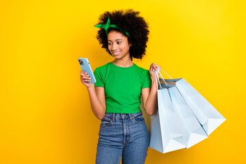 Poster - Photo of funky charming teenager schoolgirl hold store bags use smart phone online order isolated on yellow color background