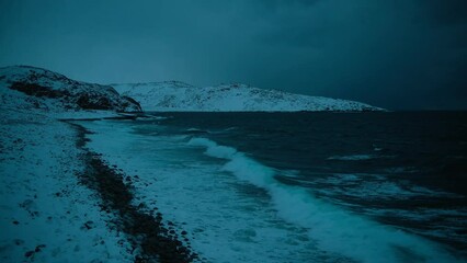 dark atmospheric footage of northern barents sea. static shot of sea waves crashing on the coast. be