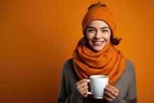 Young Woman In A Orange Scarf And Hat Drinking Cup Of Coffee On A Orange Banner With Space For Copy