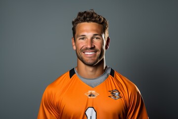 Portrait of a smiling football fan in orange jersey on grey background