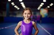 Portrait of a smiling little girl in sportswear posing at the stadium.
