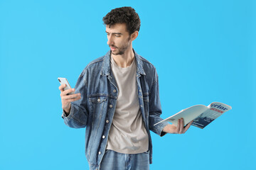 Poster - Handsome young man with mobile phone and magazine on blue background