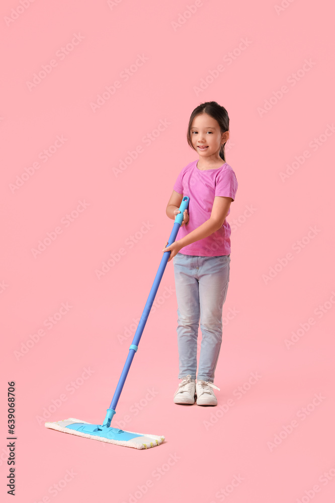 Cute little girl with mop on pink background