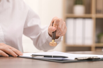 Woman stamping document at table, closeup view