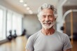 © igolaizola - Portrait of smiling senior man standing in fitness studio at the gym