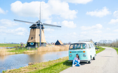 Wall Mural - woman doing a road trip with an old vintage car in the Dutch flower bulb region with tulip fields during Spring in the Netherlands, women with a old camper van