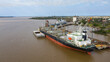 Self unloading bulk carrier cargo hatches open unloading sugar. Sugar is loaded onto barges and trucks. Aerial stern view.