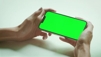 Poster - Woman with Green Screen Chroma Key Smartphone. Young adult using Internet, Play game, Watching online streaming with Mobile Phone Device. Focus on Green Display.