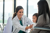 Fototapeta Dziecięca - Young female pediatric doctor teases little Asian boy before medical examination at outpatient clinic hospital, people public health care checkups, and appointment visits.