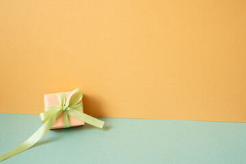 Wall Mural - Coral gift box on mint green table. orange wall background. copy space