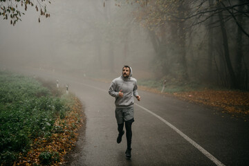 A solo runner navigating a winding forest trail, the mist adding an air of solitude and intrigue.