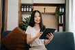 © Nuttapong punna - Young Asian woman using the smartphone and tablet on the sofa at home.