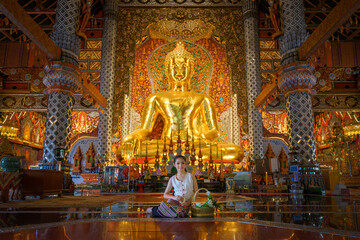 Pretty girl wearing beautiful traditional Thai dresses in Asian tradition Buddhism to make merit at Wat Sri Don Moon Temple in Chiang Mai, Thailand.