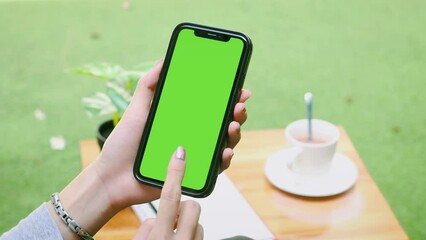 Poster - Woman with Green Screen Chroma Key Smartphone in Cafe. Asian Person using Internet, Social Media, Online Shopping with Mobile Phone Device..