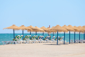 Wall Mural - Beautiful sandy beach with palm tree umbrellas and sun loungers