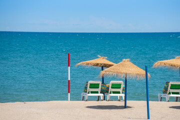 Wall Mural - Beautiful sandy beach with palm tree umbrellas and sun loungers