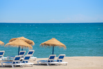 Wall Mural - Beautiful sandy beach with palm tree umbrellas and sun loungers