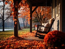 An American Flag Hangs From A Porch Of A Cozy Cottage During Autumn. Fallen Leaves And Pumpkins Set The Scene For A Homely Patriotic Fall.