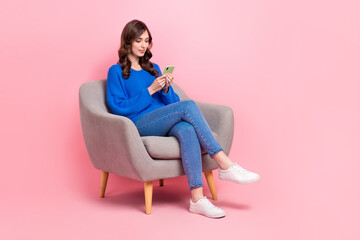 Poster - Full size photo of lovely young lady sit soft armchair hold device typing wear trendy blue garment isolated on pink color background