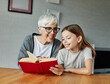 © Lumos sp - grandchild family child grandparent grandmother book reading elderly granddaughter girl  happy together read learning education woman