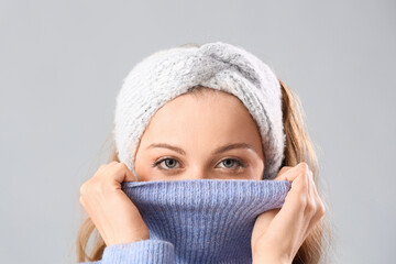 Poster - Frozen beautiful young woman in warm clothes on grey background