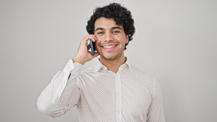 Wall Mural - Young latin man business worker smiling confident talking on smartphone over isolated white background