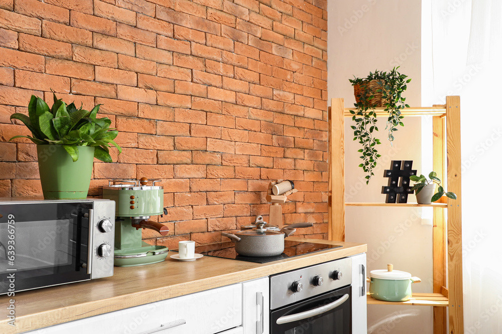 Modern electric coffee machine and electric stove on kitchen countertop