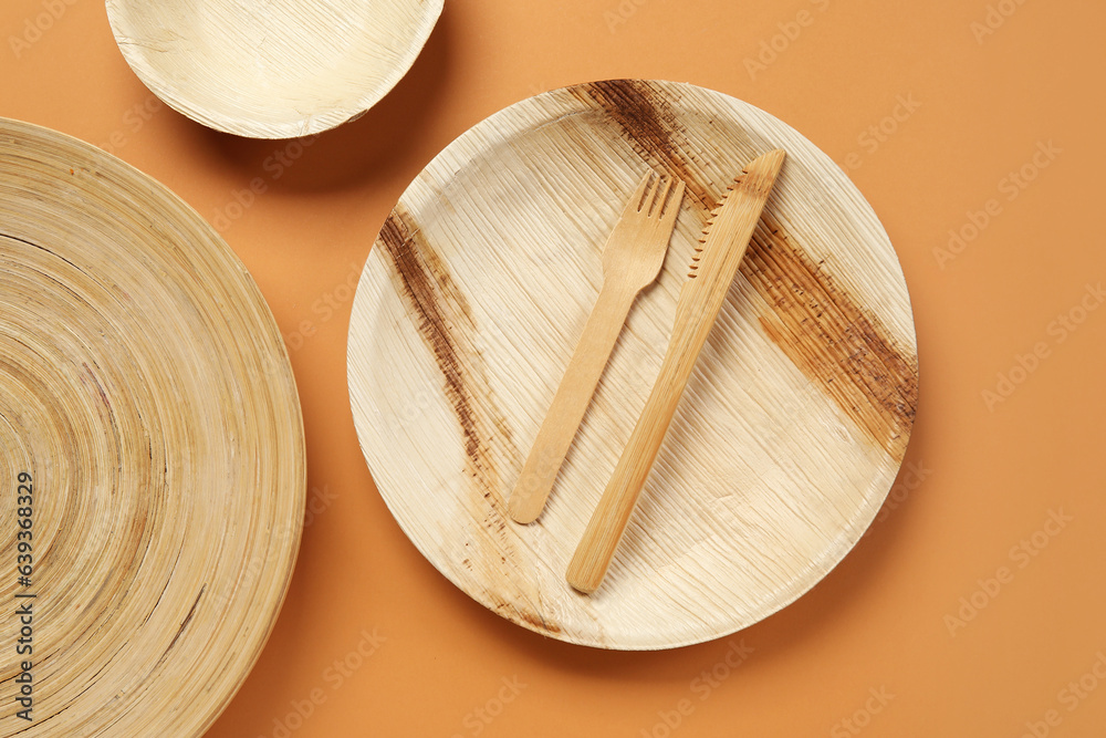 Wooden plates, bowl and cutlery on beige background