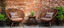 Wicker Chairs And Coffee Table Outdoors Beside Red Brick Wall