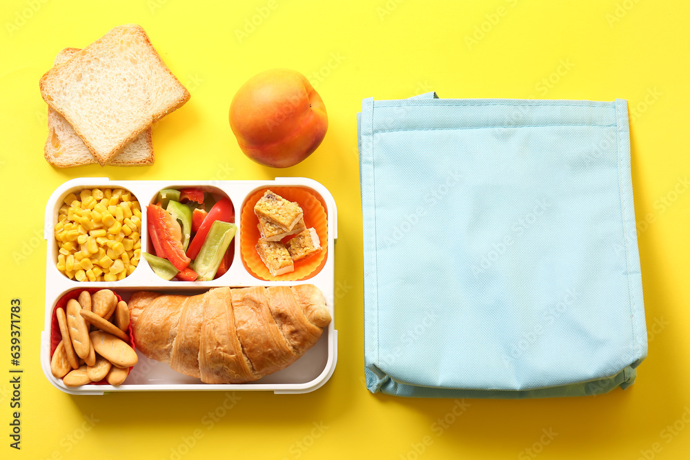 Bag and lunchbox with delicious food on yellow background