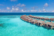 Aerial landscape of Maldives island, luxury water villas resort and wooden pier. Beautiful sky sea bay coast beach birds eye background. Summer vacation holiday and travel. Paradise aerial wallpaper