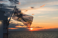 Flag Of Finland Over The Gulf Of Bothnia On The Background Of Sunset