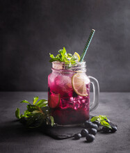 Refreshing Blueberry Mojito Or Lemonade With Lime, Mint And Ice On A Dark Background. Summer Healthy Non-alcoholic Drink Made From Fruits And Berries.