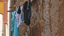 Wet Laundry Hanging On Outdoor Clothesline Over Narrow Street In Old Italian Town