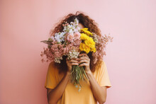 Portrait Of A Young Woman Hiding Behind A Lush Bouquet Of Different Flowers. The Girl Holds Buds And Flowers In Hands.