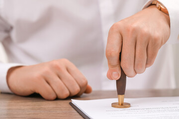 Canvas Print - Man stamping document at wooden table, closeup