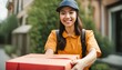 © ibreakstock - Smiling Asian postman with parcel - cardboard box, young woman delivers, online store delivery, close-up