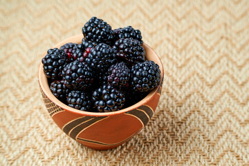 Wall Mural - Blackberries in a ceramic bowl on beige kraft fabric. View from above