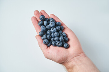 Wall Mural - blueberry in hand on white. Male hand