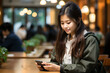 © AspctStyle - Portrait of teen girl looking at smartphone sitting at desk in university college campus classroom, Young blonde woman holding cellphone in university