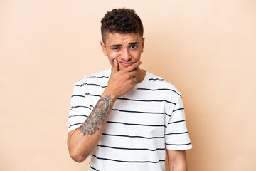 Wall Mural - Young Brazilian man isolated on beige background having doubts