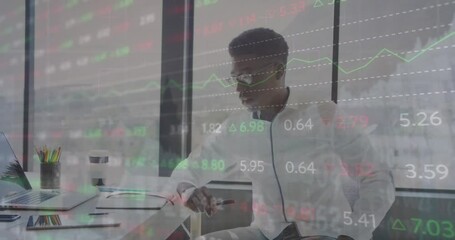 Poster - Animation of trading board over african american man holding pen looking at laptop screen in office