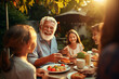Happy Senior Grandfather Talking and Having Fun with His Grandchildren, Holding Them on Lap at a Outdoors Dinner with Food and Drinks. Adults at a Garden Party Together with Kids
