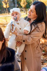 Wall Mural - mother and baby are in autumn city park, happy people walking together, family with children, playing with yellow leaves, beautiful nature, bright sunny day