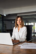 © Stock 4 You - 40s mid age European business woman CEO using laptop for work sitting at table in office, looking at camera. Smiling Latin Hispanic mature adult businesswoman using pc digital computer, vertical shot